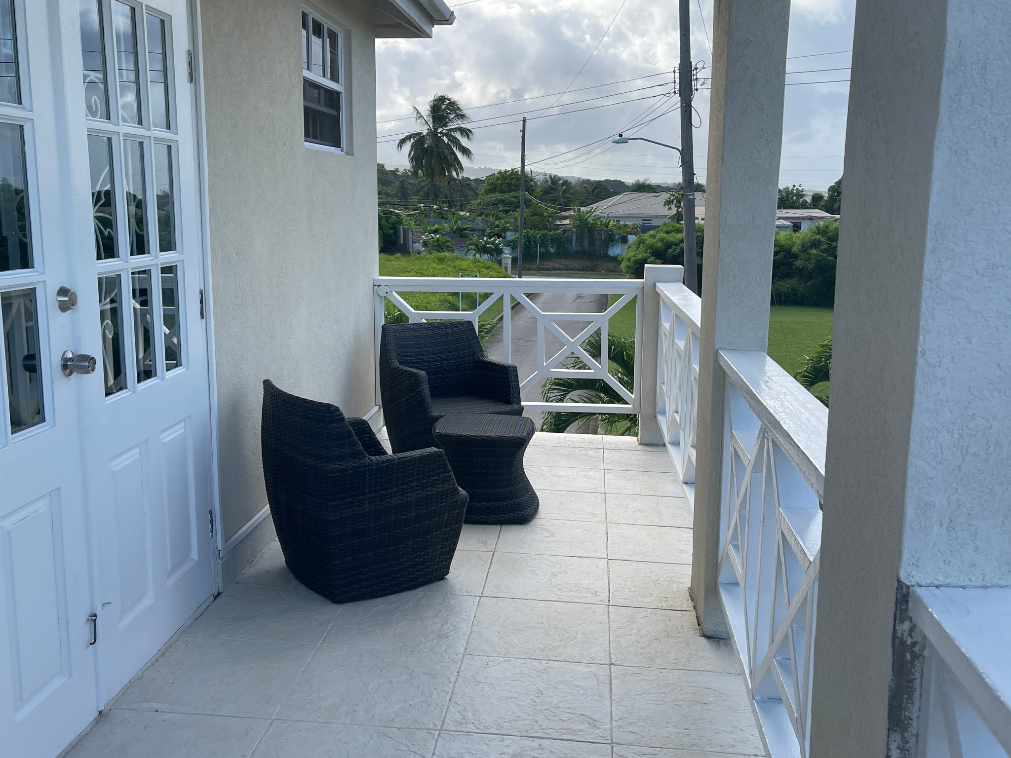 Holland Park Villa front balcony with wicker chairs and tropical views